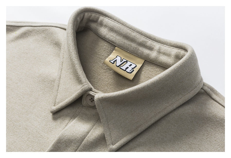 Close-up of a beige-gray shirt jacket’s wide collar, button, and sewn NB neck label.