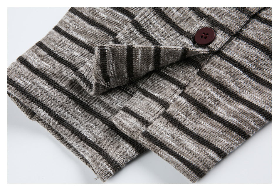 Close-up of a folded cuff and button on a gray and black striped knit garment.