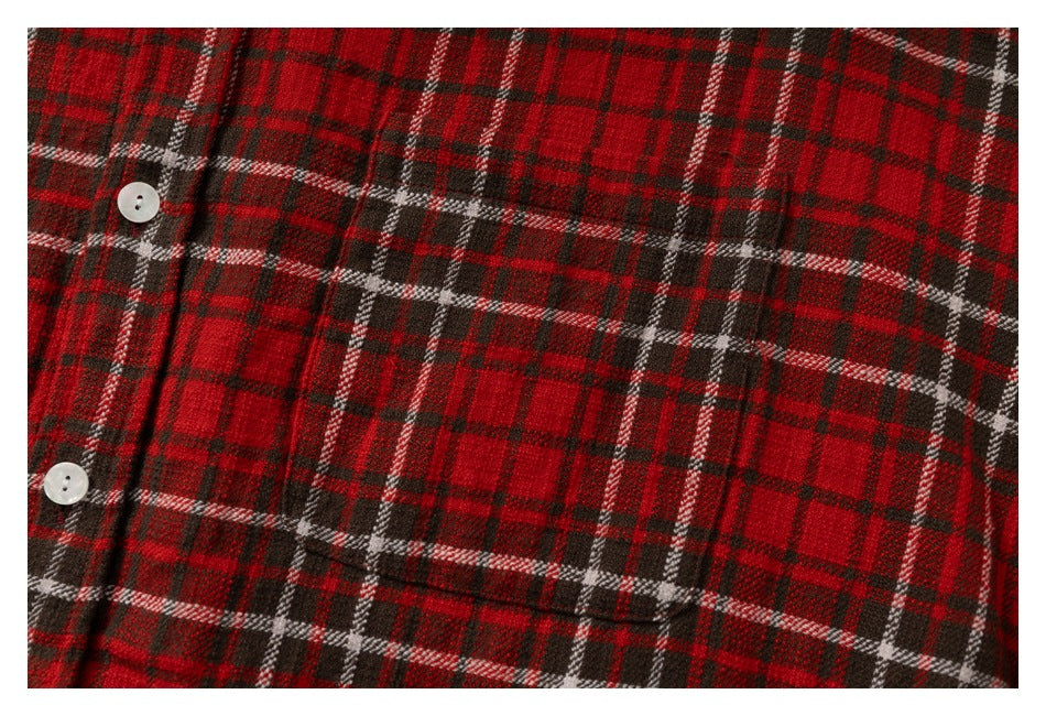 Close-up of a chest pocket and button on red, black, and white plaid fabric.
