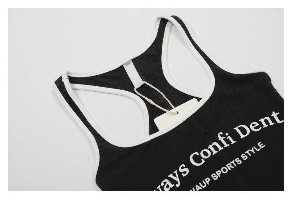 Angled close-up of a black tank top with white trim, a hang tag, and part of its white printed lettering.