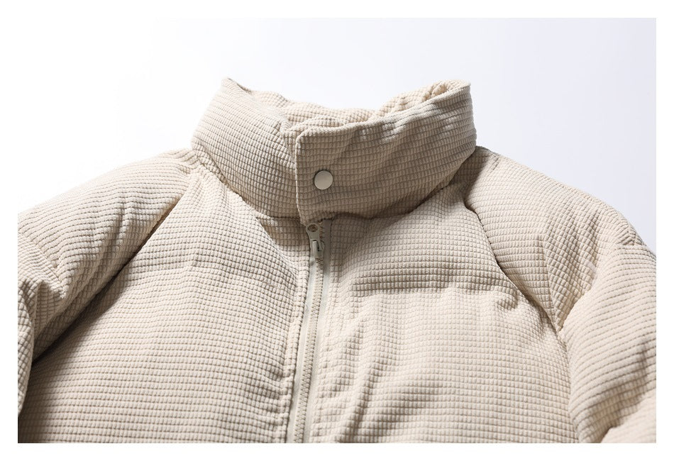 Close-up of the cream padded jacket's front, highlighting its high snap collar, zipper, and textured surface.