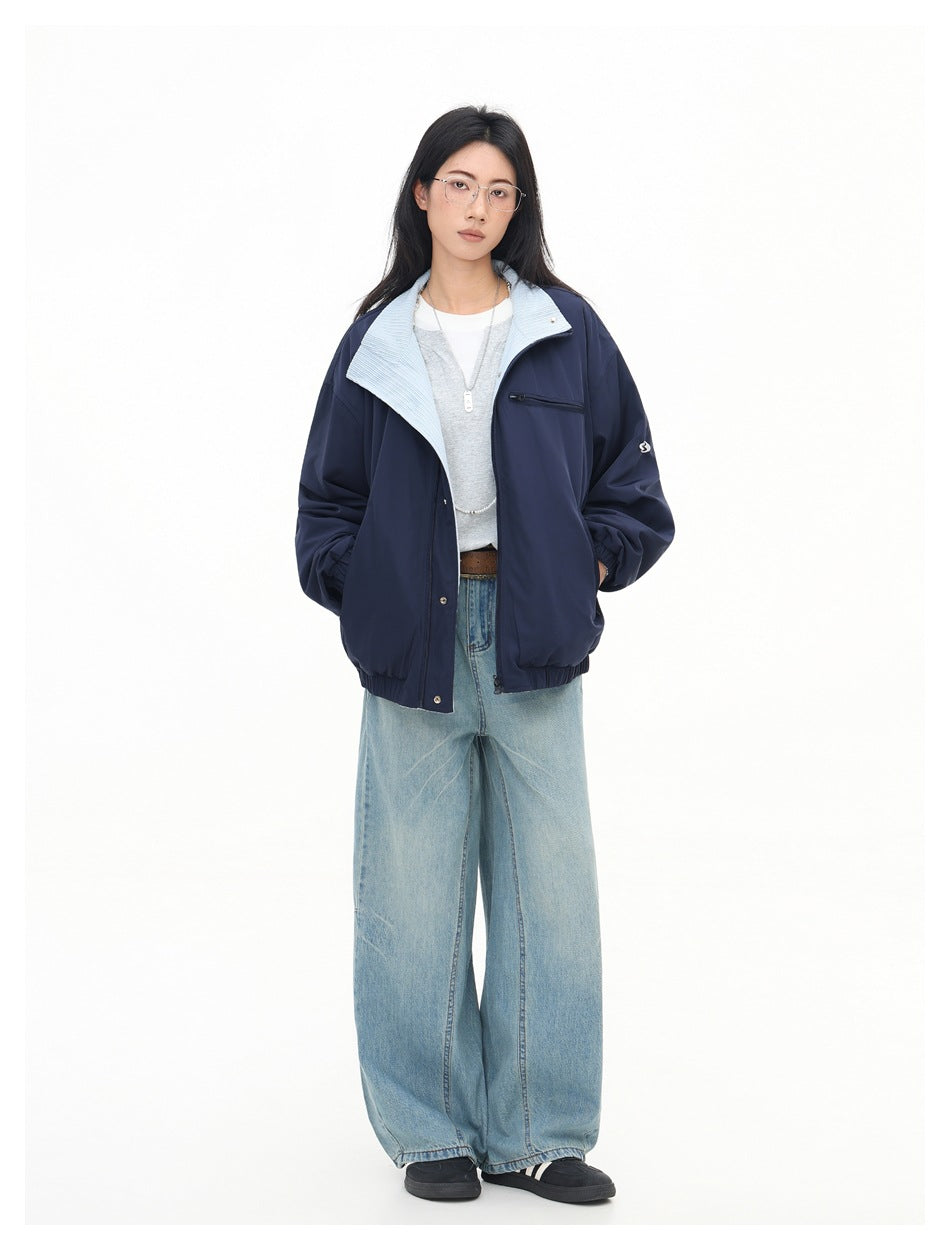Model wearing an open navy jacket with light blue striped collar over a gray top and wide-leg light wash jeans