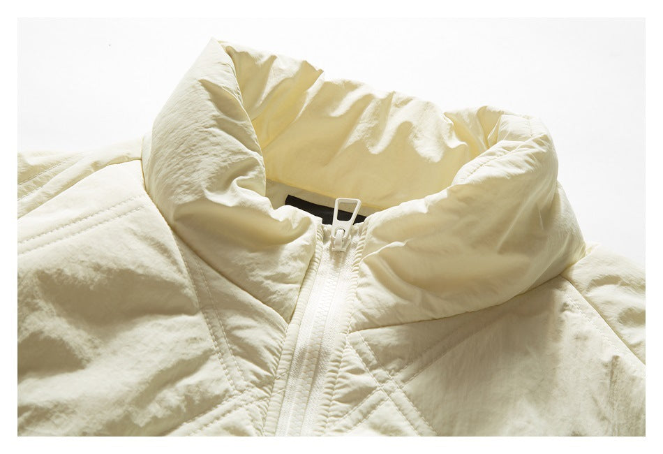 Close-up of an ivory quilted jacket's tall stand collar and front zipper.