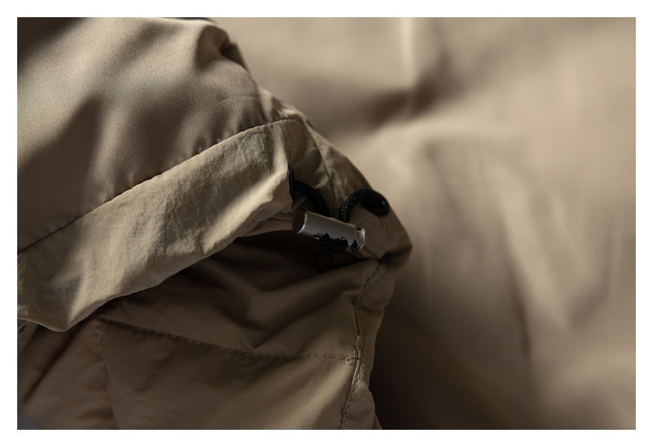 Close-up of a tan padded jacket hood with a black drawcord and toggle.