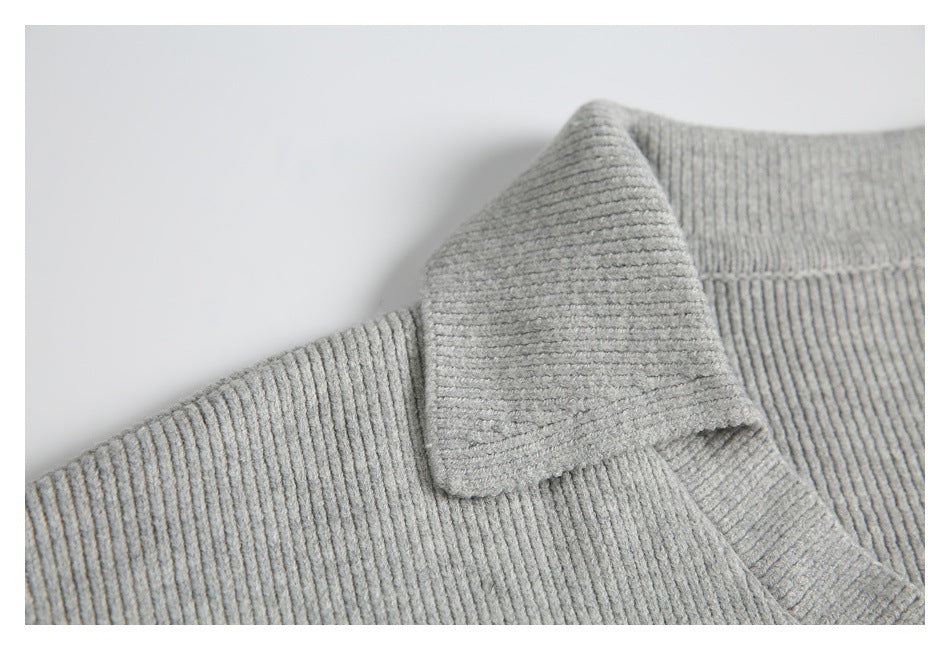 Close-up of the light gray sweater’s folded rib-knit collar and V-neck opening.