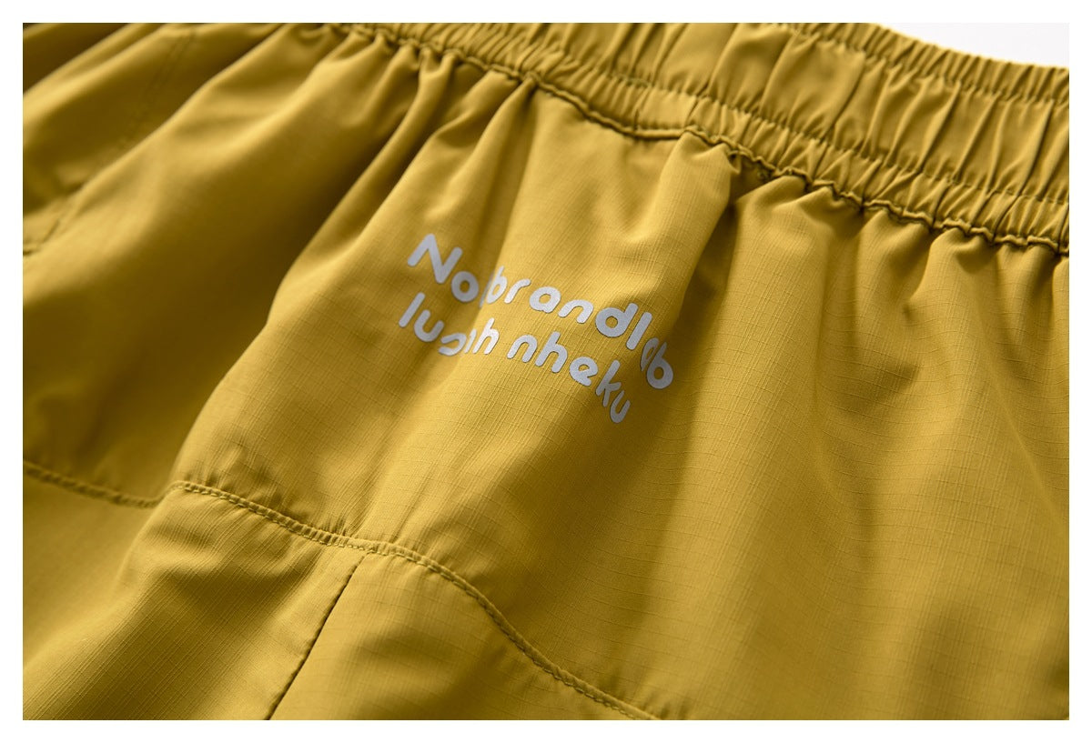 Close-up of white lettering on the mustard shorts below the gathered elastic waistband.