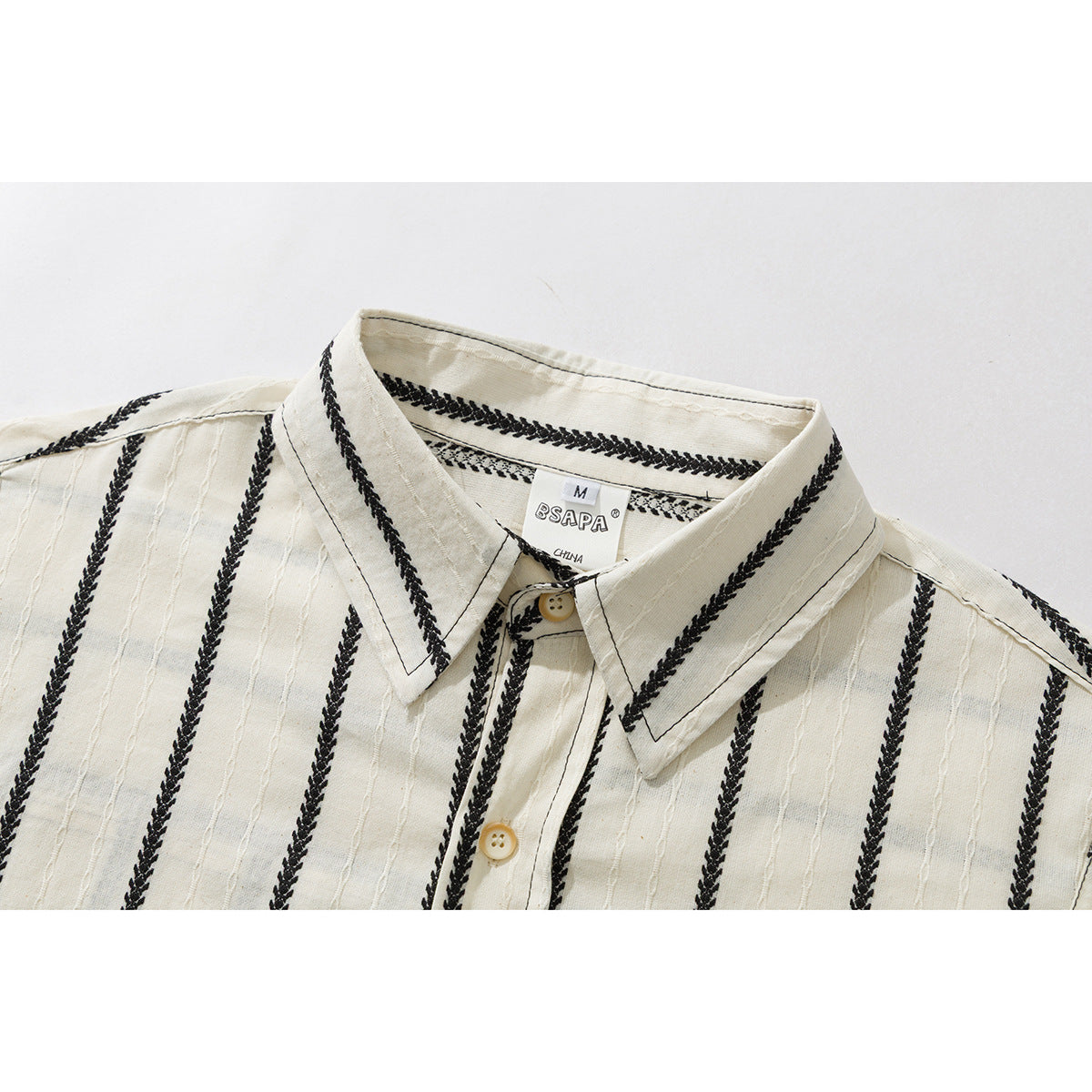 Close-up of a cream shirt collar and upper front with black braided vertical stripes and cream buttons.