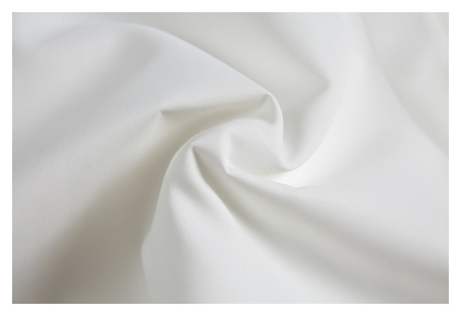 Close-up of white garment fabric draped into soft folds, showing its fine diagonal weave.