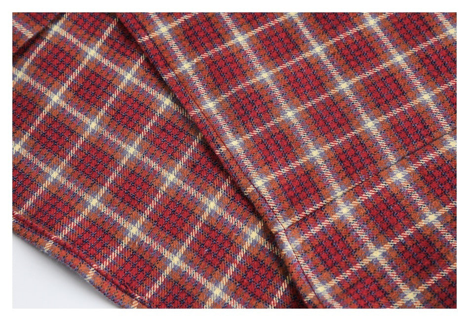 Close-up of red, navy, and cream plaid shirt fabric showing a folded edge and stitching.