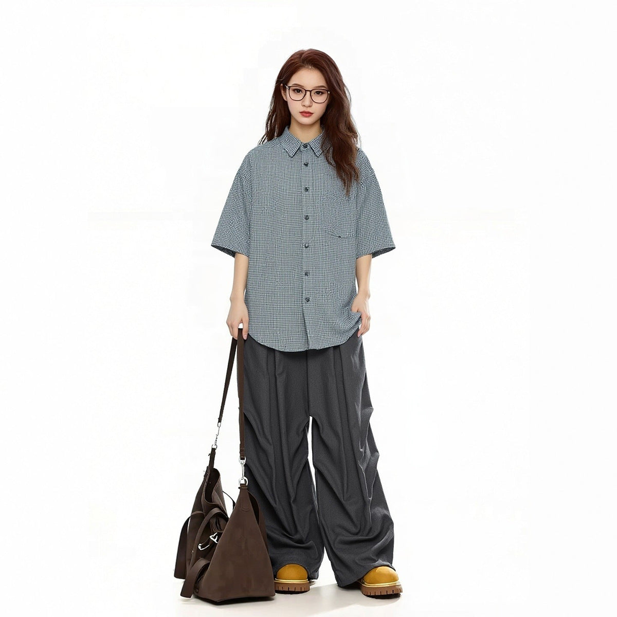 Model wearing a gray checked short-sleeve button-up shirt with dark wide-leg pants.