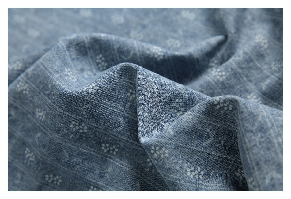 Macro view of blue patterned fabric gathered into folds, showing its small white motifs and texture.