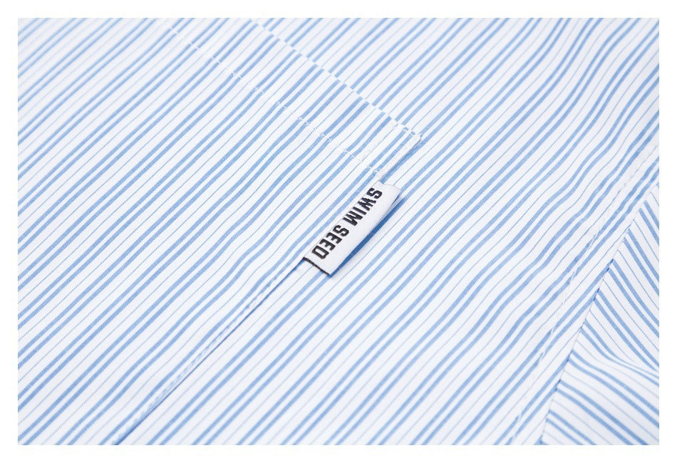 Close-up of a small sewn label on white fabric with fine blue stripes.