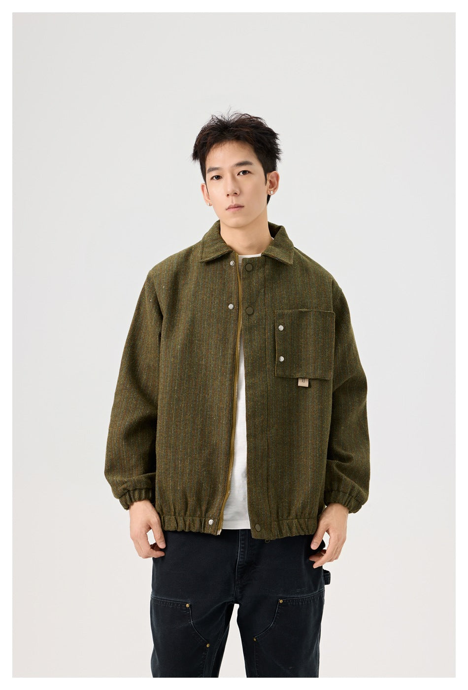 Front view of a man wearing an olive-brown textured jacket with a pointed collar, snap front and large chest pocket.