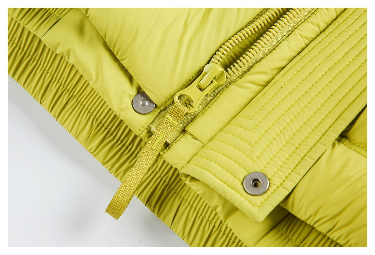 Close-up of a chartreuse jacket's front zipper, snap-fastened storm flap, and gathered hem.