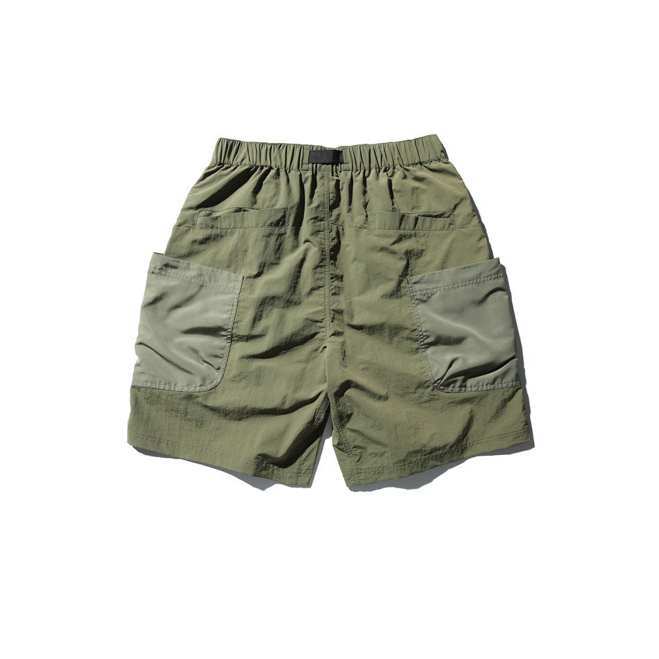 Back view of olive green utility shorts with an elastic waistband and large patch pockets.