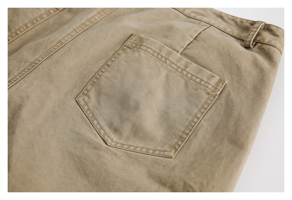 Close-up of a stitched patch pocket and belt loop on tan trousers.