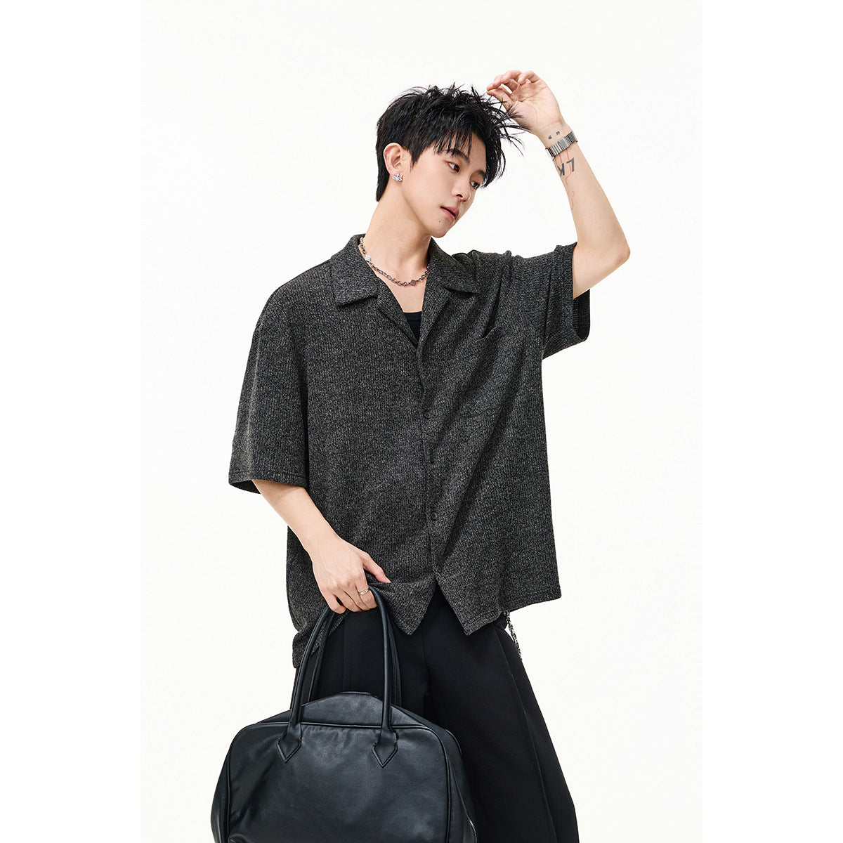 Model wearing a charcoal gray short-sleeve button-up shirt with a notched collar and black trousers.
