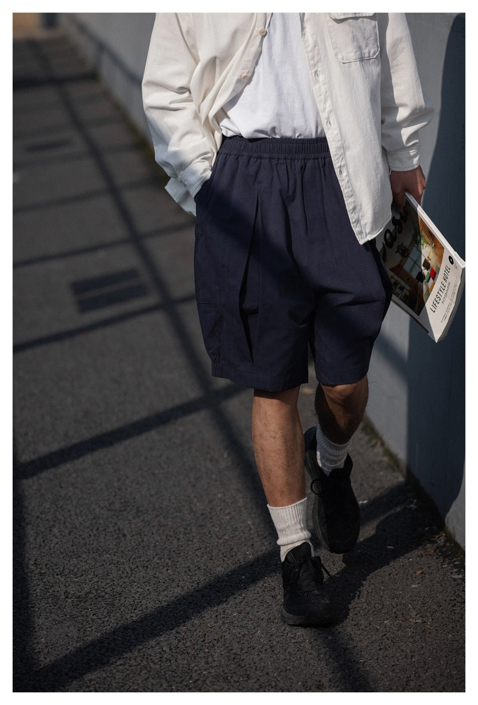 Close view of loose navy shorts with an elastic waistband, worn with a white shirt.