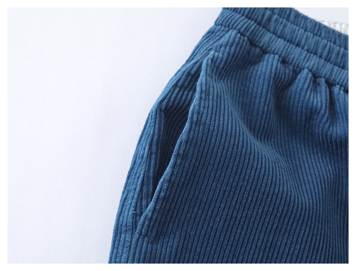 Close-up of a side pocket opening and elastic waistband on blue ribbed corduroy pants.