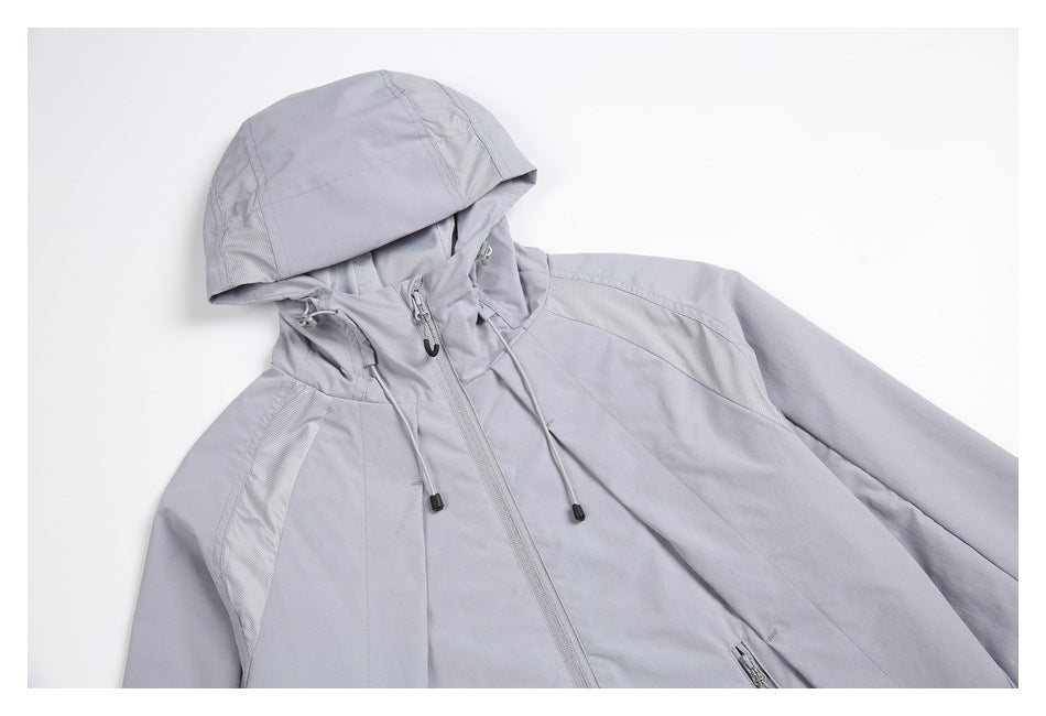 Angled view of the pale gray jacket's hood, drawcords, front zipper, and upper panels.