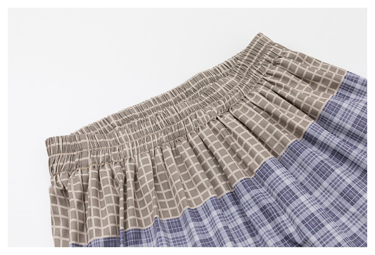 Angled close-up of the elastic waistband and taupe and lavender plaid upper skirt panels.