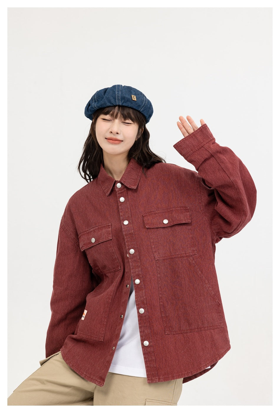 Close front view of a model wearing a muted red button-front overshirt with two flap chest pockets.