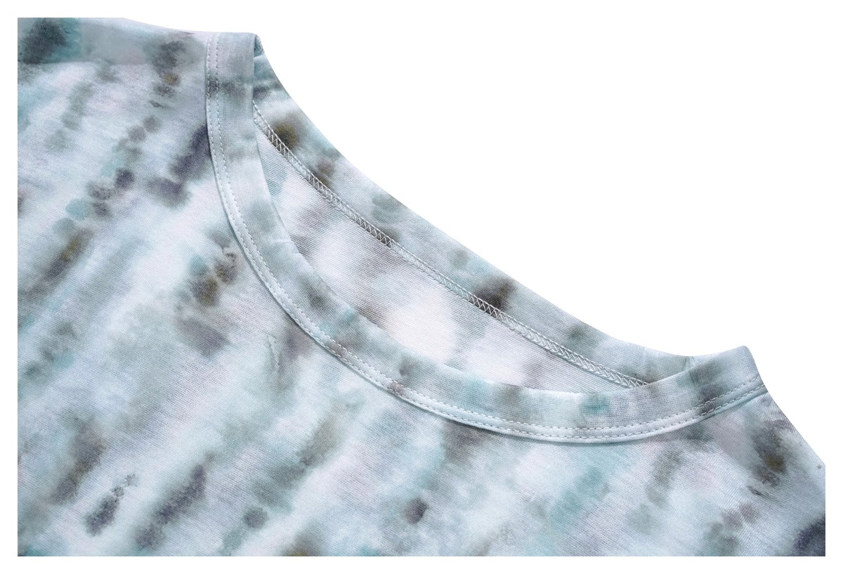 Close-up of the wide neckline and stitched shoulder seam on a pale blue-gray tie-dye top.