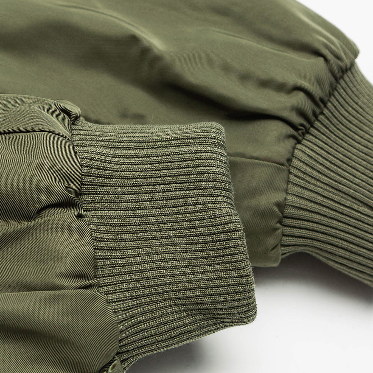 Close-up of an olive jacket sleeve with a wide ribbed cuff and gathered fabric.