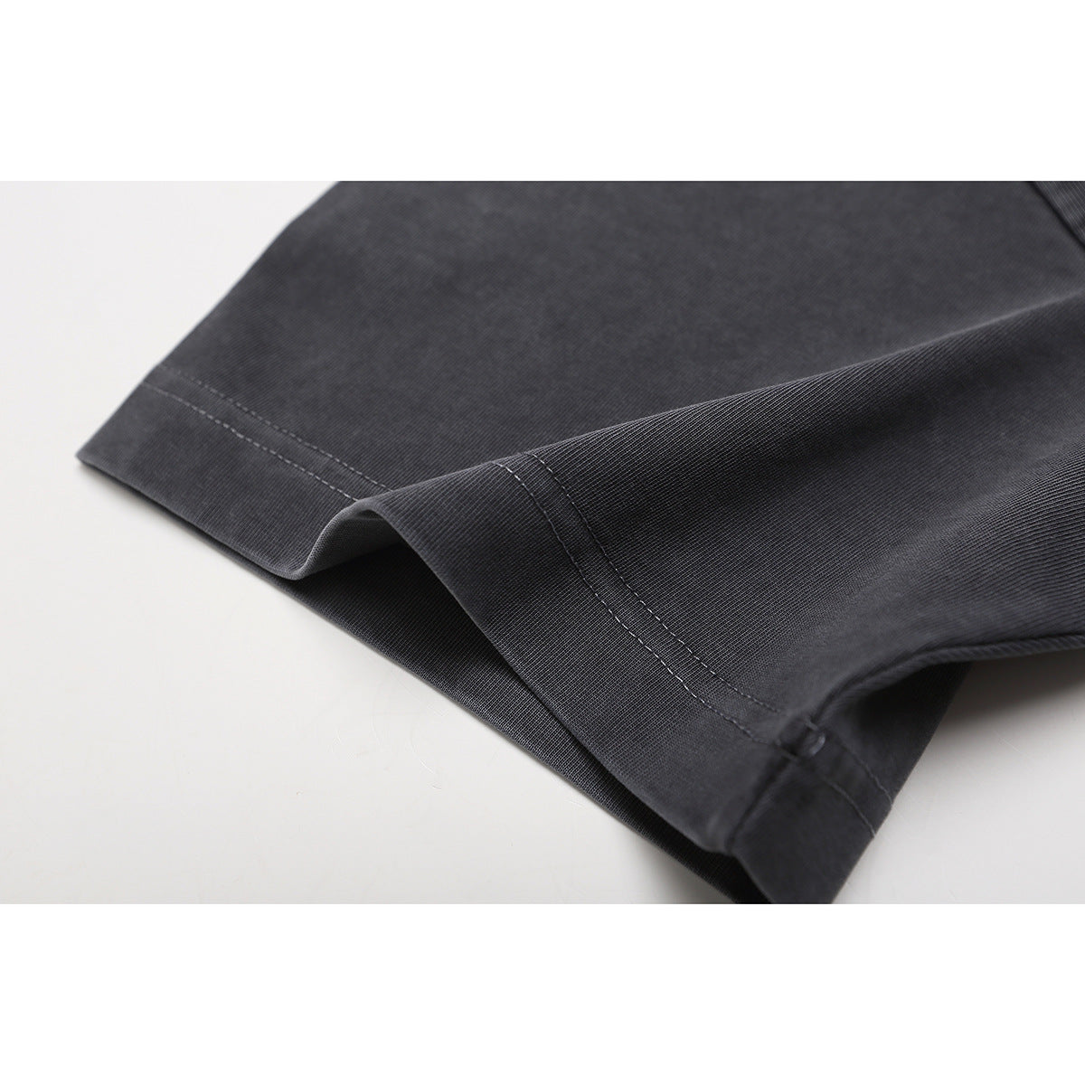 Close-up of a charcoal gray T-shirt sleeve hem with visible double-row stitching.