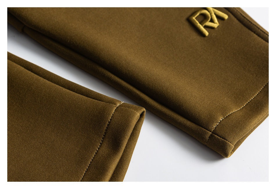 Close-up of olive-brown pant legs showing stitched hems and a small tonal embroidered emblem.