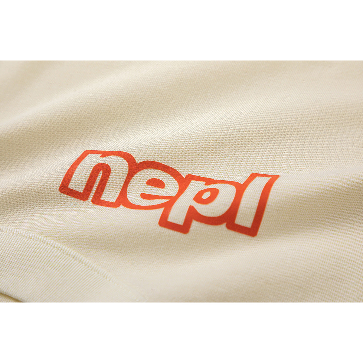 Close-up of red outlined lettering printed on cream T-shirt fabric.
