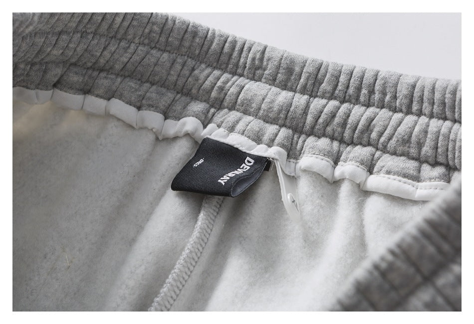 Close-up of gray sweatpants' elastic waistband interior, white lining, and a sewn black label.
