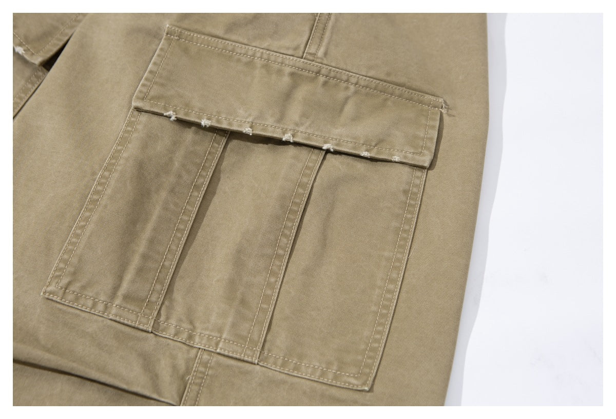 Close-up of a large stitched cargo pocket on khaki trousers, with a flap and lightly frayed edge.