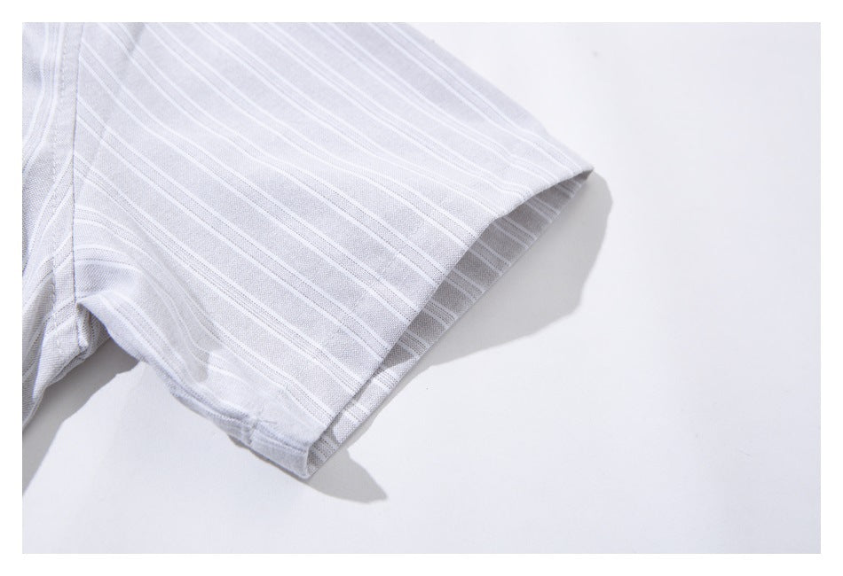 Close-up of a short sleeve on a pale gray shirt with thin white stripes, showing the hem and stitching.