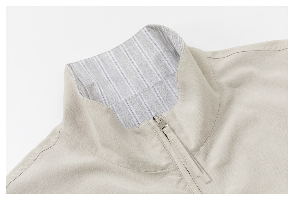 Close-up of a beige jacket collar, striped inner facing, and front zipper.