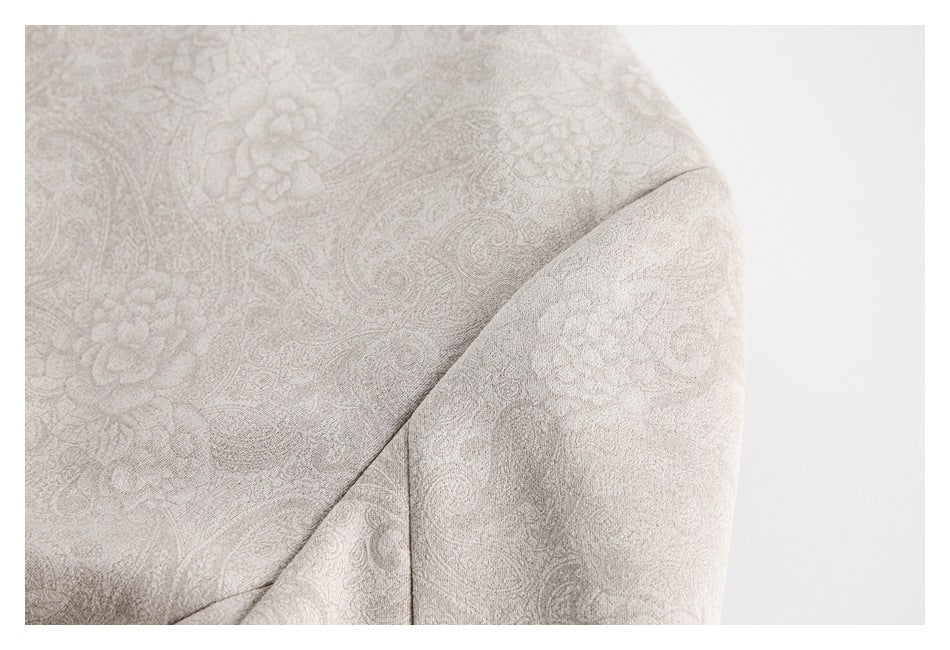 Close-up of light taupe paisley fabric and a curved garment seam.