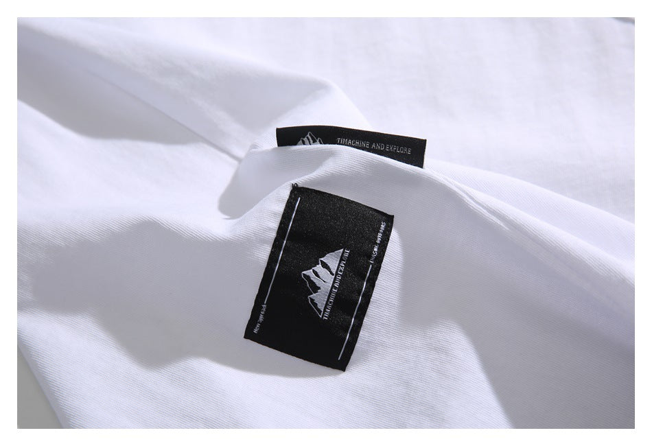 Close-up of black sewn-in labels on a white T-shirt, including a mountain graphic and English lettering.