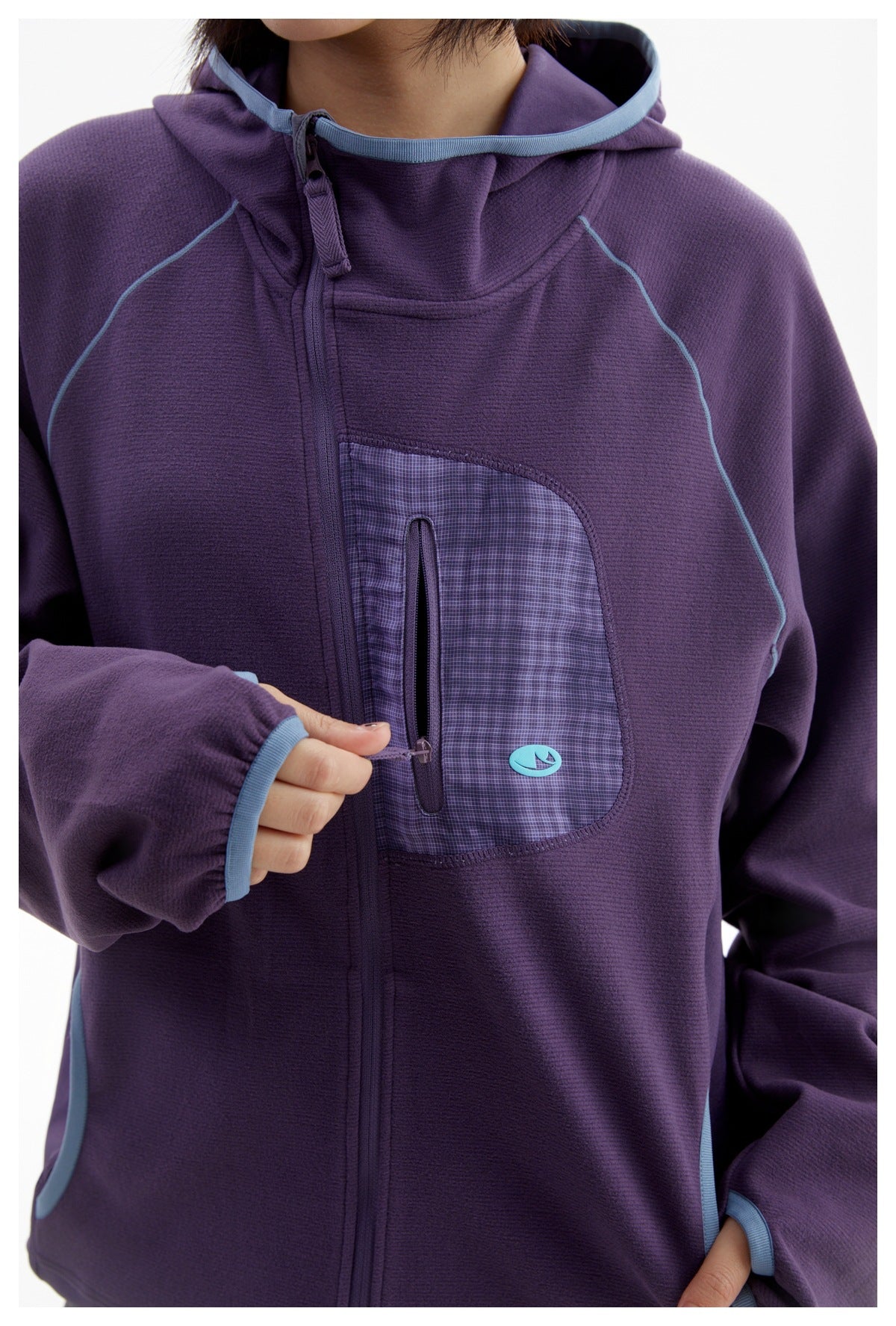Close-up of a purple hooded jacket showing blue piping, a checked zip chest pocket, and the front zipper.