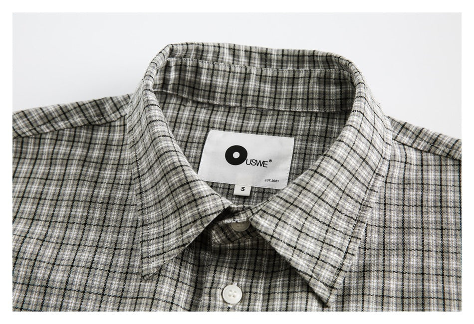 Close-up of the gray plaid shirt collar, white buttons, and sewn-in brand label.