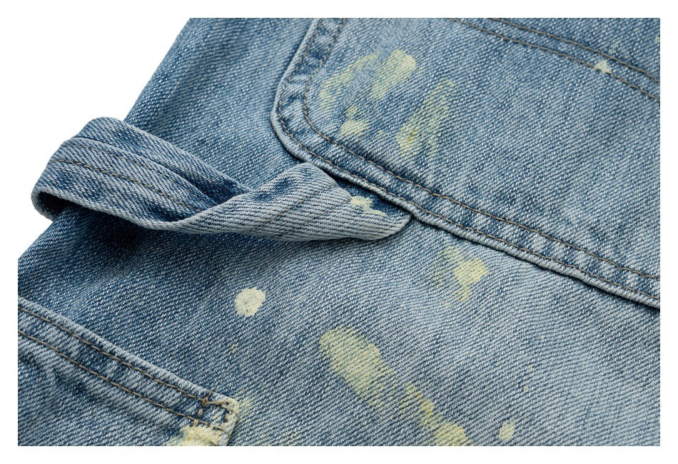 Close-up of a folded denim edge and seams with scattered pale distressed marks.