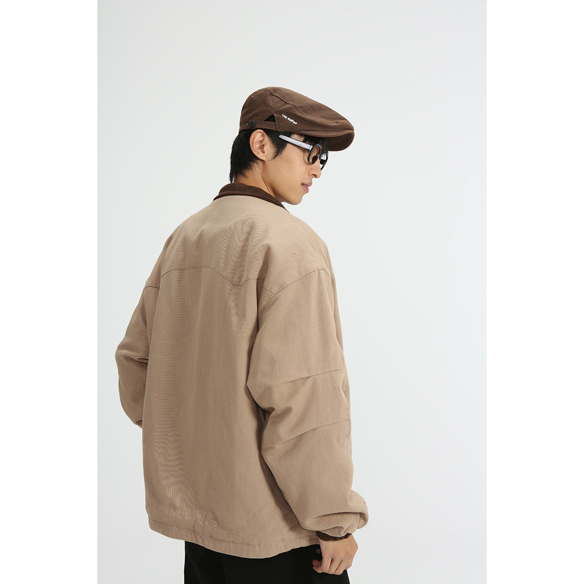 Rear view of a model wearing a tan jacket with a dark brown collar and gathered cuffs.