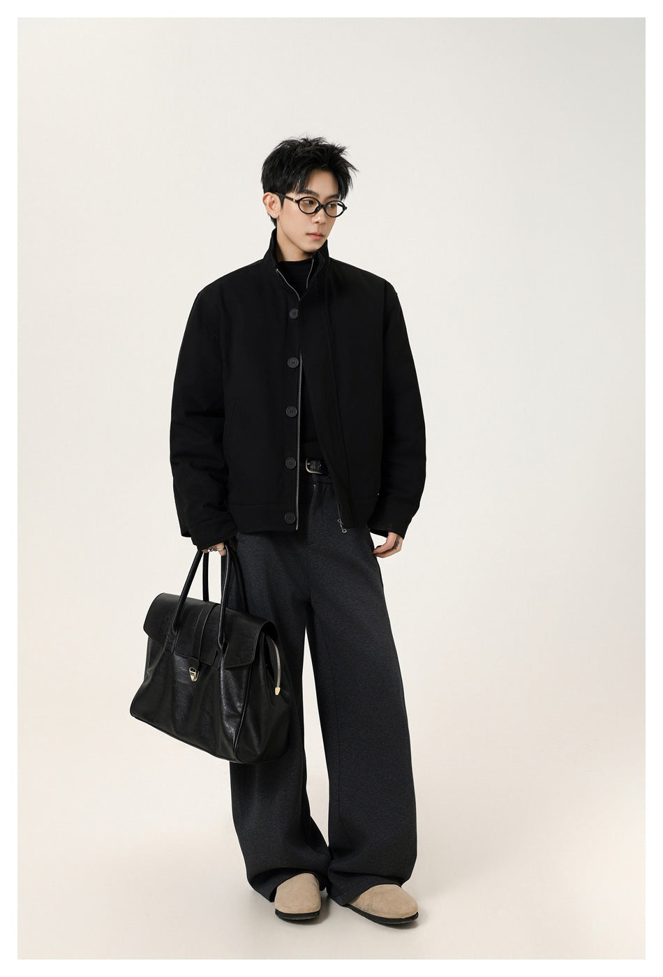 Full-length model wearing a black button-front jacket and charcoal wide-leg trousers, carrying a black handbag.