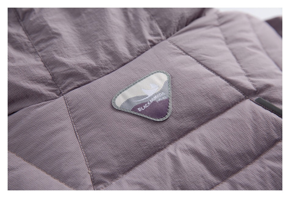 Close-up of a sewn brand patch on the mauve quilted jacket.