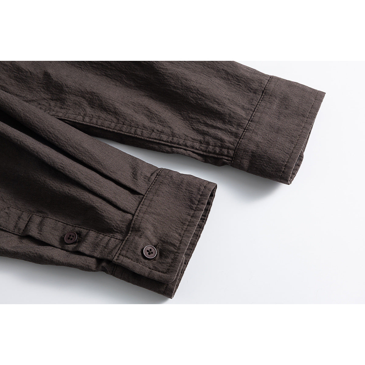 Close-up of dark brown shirt sleeves and buttoned cuffs.