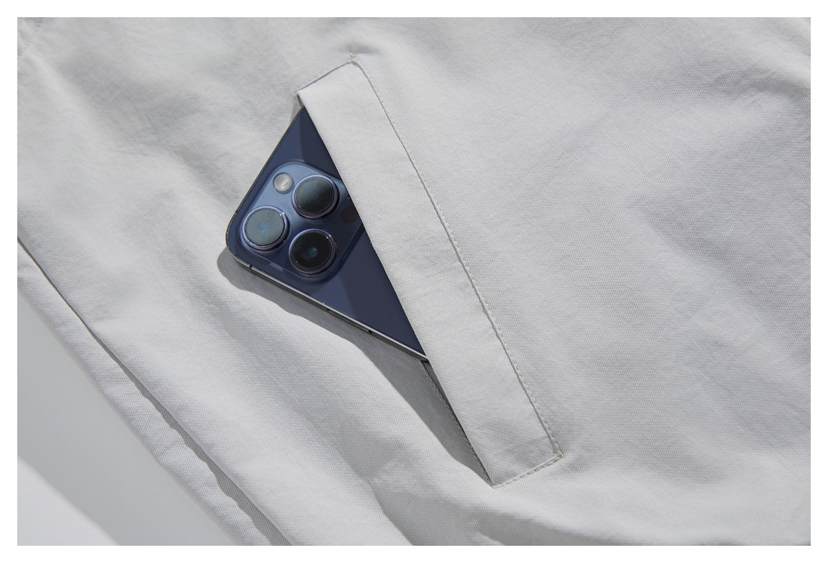 Close-up of a light gray garment pocket holding a dark smartphone.