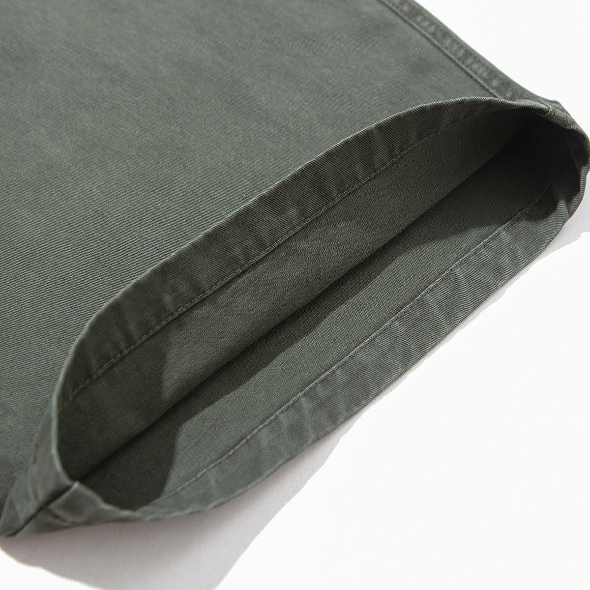 Close-up of a gray-green pant leg hem turned back to show the inside and stitching.