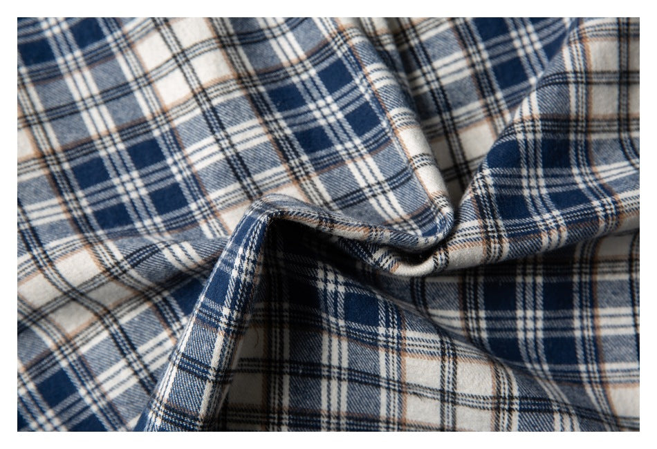Close-up of navy, cream, and tan plaid shirt fabric folded to show its drape.