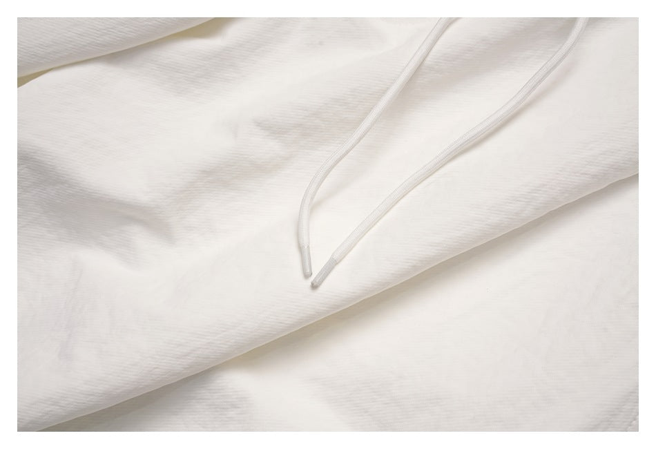 Close-up of the off-white trousers' drawcord ends against the fabric.