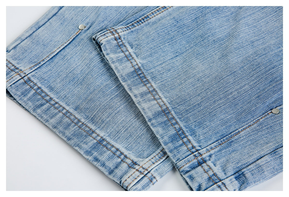 Close-up of light blue faded denim jeans with orange stitching and metal rivets.