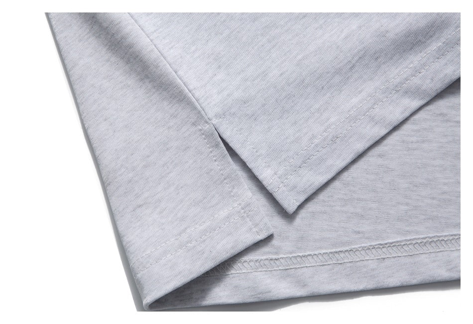Close-up of overlapping stitched edges and an overlocked seam on light gray fabric.